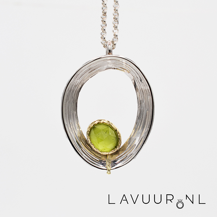 Zilveren hanger in de vorm van een ei-vormige/ovale circel met strepen gedecoreerd, onderin de circel een roosslijpsel peridoot in gouden zetting