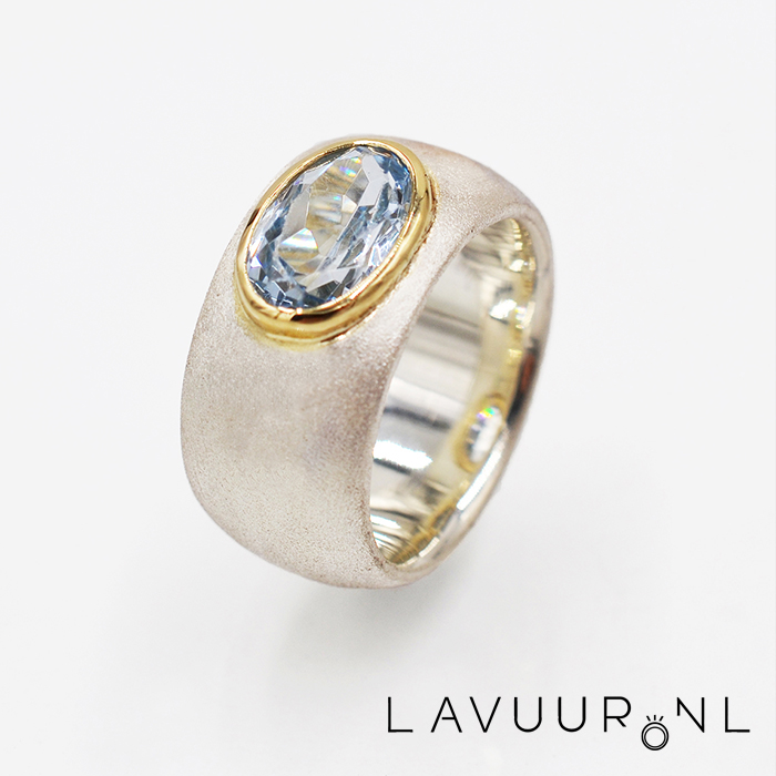 Zilveren ring, van breed gematteerd zilver, met grote ovale aquamarijn in gouden zetting