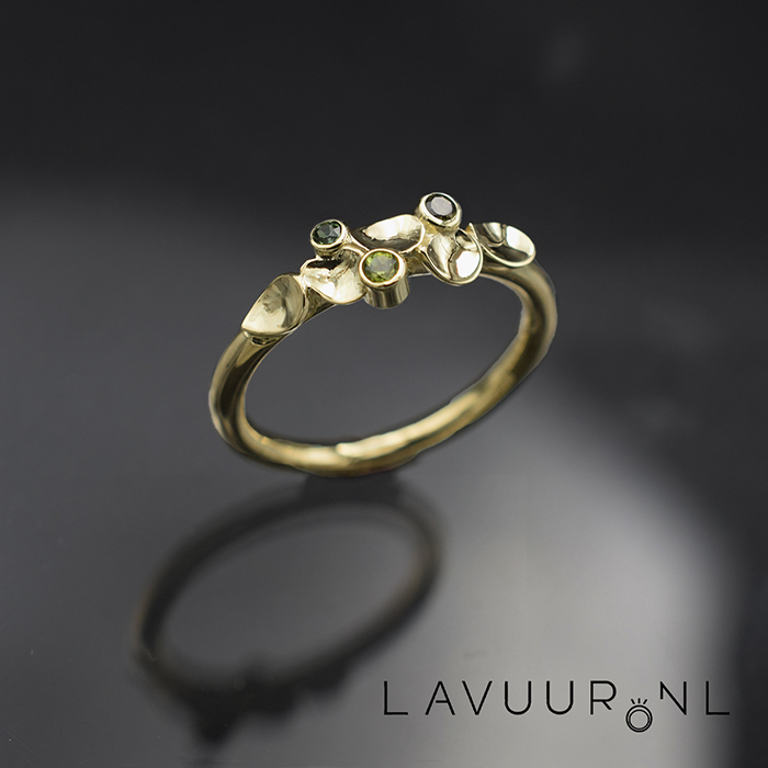 Gouden ring gedecoreerd met vijf holgemaakte blaadjes die er individueel opliggen, geflankeerd door drie verschillend gekleurde toermalijntjes