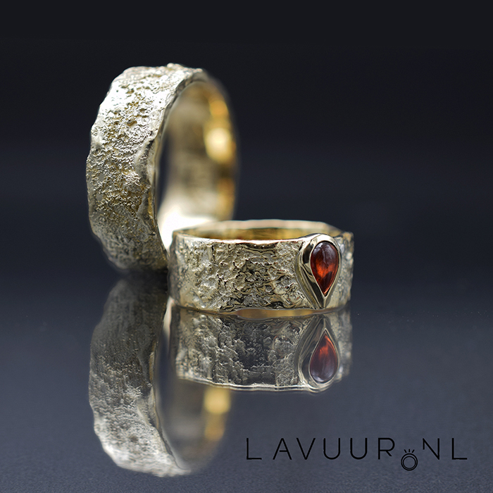Gouden trouwringen, ruw en gesmolten decoratie, waarvan een met een peervormige granaat