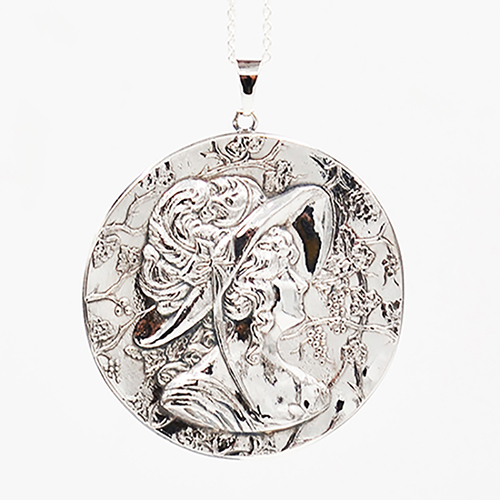zilveren hanger waarin een vrouwenhoofd met sierlijke bloemenhoed gestempeld is