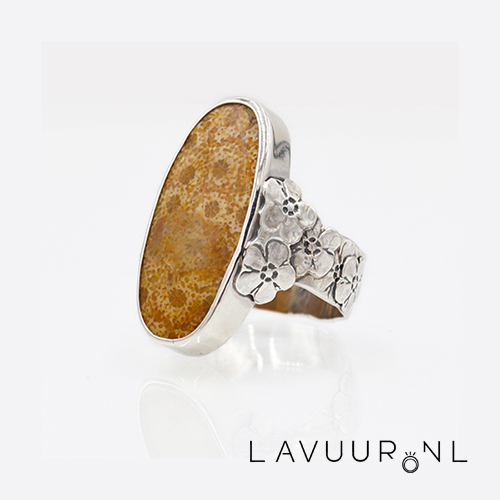 zilveren ring versierd met grote gestempelde bloemen op de band met in het midden een grote ovale fossiel koraal