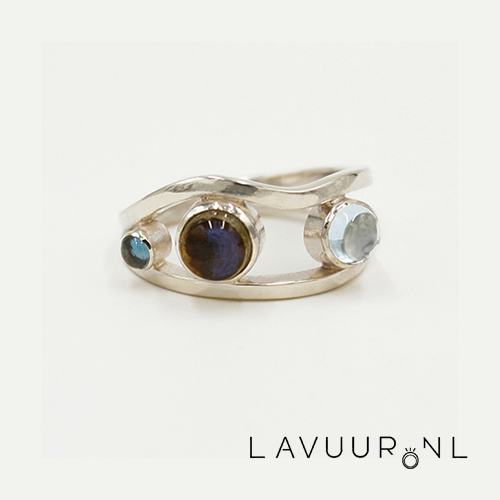 zilveren ring bestaande uit twee banden, waarvan de bovenband een golf patroon volgt, tussen de twee banden zijn drie edelstenen geplaatst, een kleine ronde topaas, een middelgrote ronde labradoriet en een ronde lichtblauwe topaas