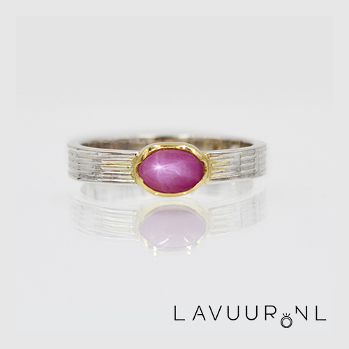 zilveren ring met rechte band met lichte groeven er in met in het midden een onregelmatige gouden zetting met ovale sterrobijn